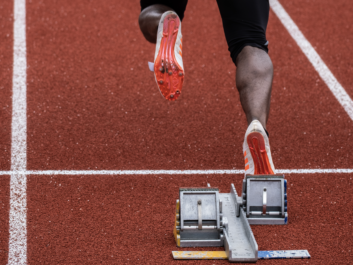 A close up of a black athletes feet as they start a race on a track.