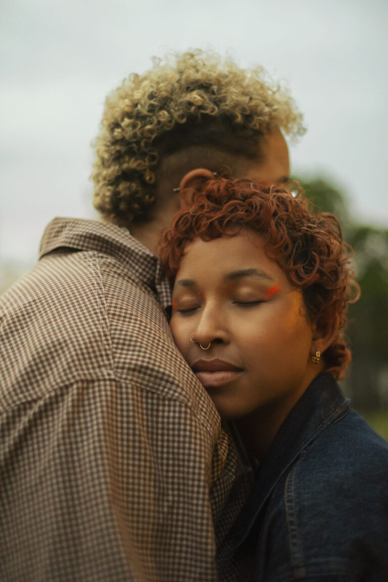 A trans couple embracing outside at dusk