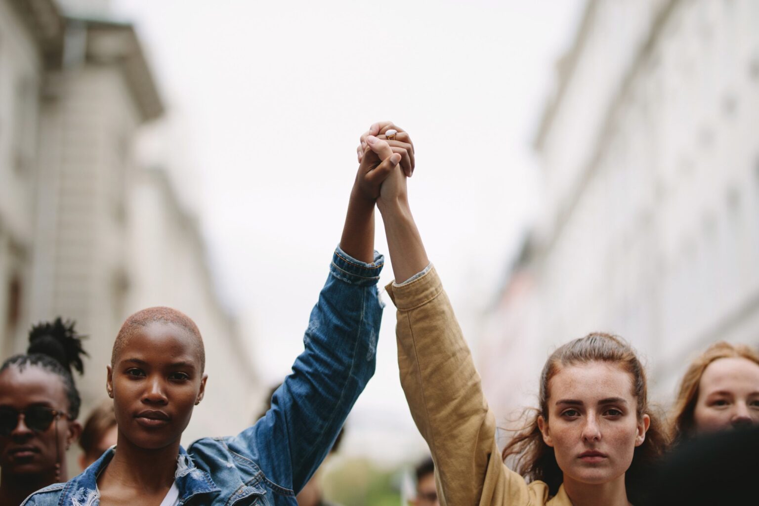 Black and white person holding each other hand up in the air